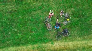 Imagem ilustrativa vista de cima de jovens sentados ao lado de suas bicicletas.